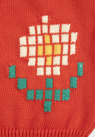 Tela roja tejida con un diseño pixelado de una flor blanca y amarilla, y hojas geométricas verdes.