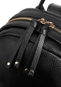 Zaino in pelle nera con superficie texture, cerniera dorata e linguette di apertura a contrasto. Rivetti decorativi completano il design.