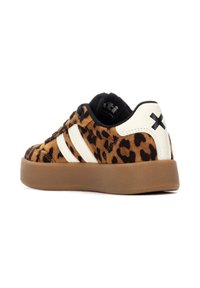 Zapatillas con estampado de leopardo, con parte superior de ante marrón, detalles en piel blanca, cordones negros y suela de goma marrón. Tres franjas blancas en el costado.