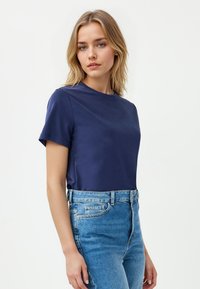 Navyblauwe T-shirt met korte mouwen en een ronde hals, gemaakt van gladde stof, gecombineerd met lichtblauwe hoge taille denim jeans.