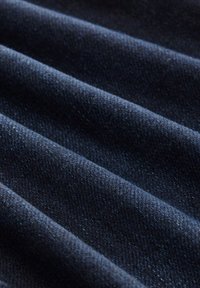 Tamno plavi denim tkanina s teksturiranom površinom, koja ima istaknute horizontalne rebraste linije i mekan završetak. Fina i detaljna tkanina.