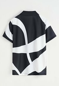 Chemise à manches courtes en tissu noir et blanc avec de grands motifs abstraits. Le col est structuré et la texture semble lisse et légère.