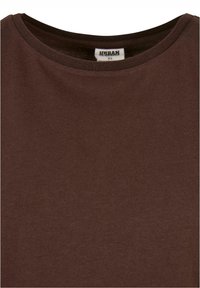 T-shirt marron à col rond en taille extra petite avec une étiquette de marque visible "Urban" à l'intérieur du col.