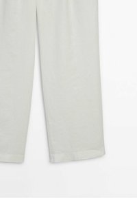 Pantalon en lin gris clair avec une coupe droite, présentant une texture lisse et des ourlets retroussés. Aucun embellissement ou motif visible.