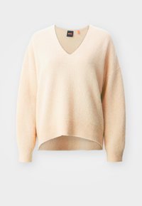 Pull tricoté couleur crème à manches longues avec col en V, poignets et ourlet côtelés, épaules légèrement tombantes, étiquette de la marque visible à l'intérieur du col.