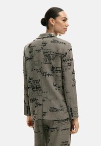 Hall halliülikond mustade käsitsi joonistatud mustritega, struktureeritud disain, sälguga krae ja nööpidega varrukad. Õhuke lõige ja sile tekstuur.