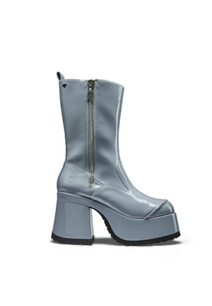 Cizmă platformă din piele lacuită albastră, cu toc gros, fermoar lateral și decupaj mic în formă de inimă lângă vârf.