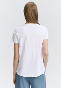 Witte katoenen t-shirt met korte mouwen, ronde halslijn en een relaxte pasvorm. Kenmerkt zich door een gladde textuur en een lichte kromming aan de zoom.