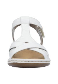 Sandalia de cuero blanco con correas cruzadas, punta abierta y correa ajustable al tobillo. Plantilla suave de color tostado y suela exterior de color marrón claro.