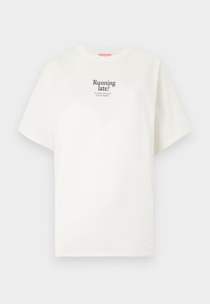 Hvit T-skjorte med korte ermer og svart tekst "Sen? Ingen bekymring, ta på deg favorittsneakersene dine" trykt på brystet.