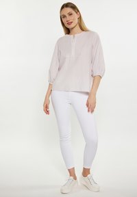 Lyserød og hvid stribet bluse med rund halsudskæring, knaplukning og 3/4 pufærmer, parret med hvide skinny jeans og hvide sneakers.