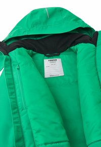 Grüne isolierte Jacke mit Kapuze, ausgestattet mit schwarzem Innenfutter, einer vorderen Reißverschlusstasche und einem Etikett mit Pflegehinweisen im Inneren.