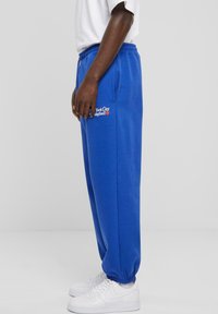 Blå bomullssweatpants med elastisk midje og mansjetter. Har side lommer og "New York City Basketball" brodert på låret.