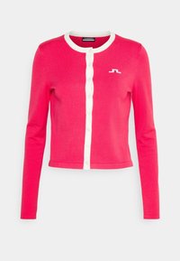 Rosa stickad kofta med långa ärmar, vit knappslå och rund krage. Har en liten logotyp i vitt på vänster sida.