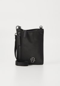 Čierna nylonová crossbody taška so striebornými kovovými doplnkami, jedným zipsom a nastaviteľným ramenným popruhom. Na prednej strane má embosovaný logo.
