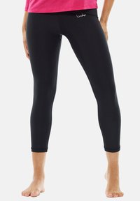 Mustat capri legginsit, jotka on valmistettu joustavasta kankaasta, ja niissä on sileä pinta sekä huomaamaton logo vyötäröllä. Nilkkapituus ja tiukka malli.