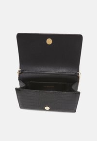 Černá kožená peněženka s texturovaným krokodýlím vzorem, zlatým cvokem na zavírání a vnitřními přihrádkami. Logo embosováno uvnitř.