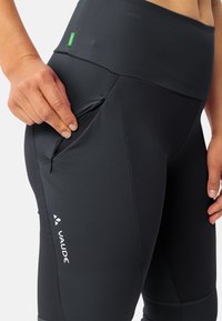 Leggings sportivi neri con una trama liscia, dotati di una tasca con zip sulla coscia e una vita alta. Logo Vaude visibile.