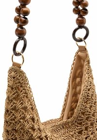 Beige geweven tas met grote houten kralen als handvat en ronde donkere ringen die het hengsel aan de zijkanten van de tas verbinden.