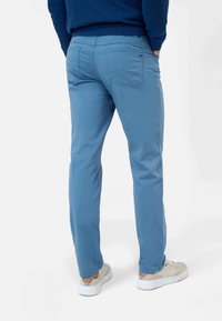 Světlé modré liché kalhoty s designem zadní kapsy, vyrobené z hladké tkaniny. Mají slim fit a elastický pas pro pohodlí.