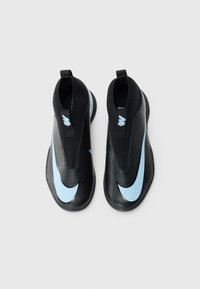 Une paire de chaussures de sport noires à enfiler avec des logos Nike en swoosh bleu clair sur un fond blanc uni, vue d'en haut.