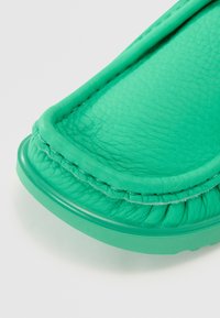 Pantofii slip-on din piele verde au o finisare texturată, vârf rotund și detalii cusute pe margine pentru un plus de confort.