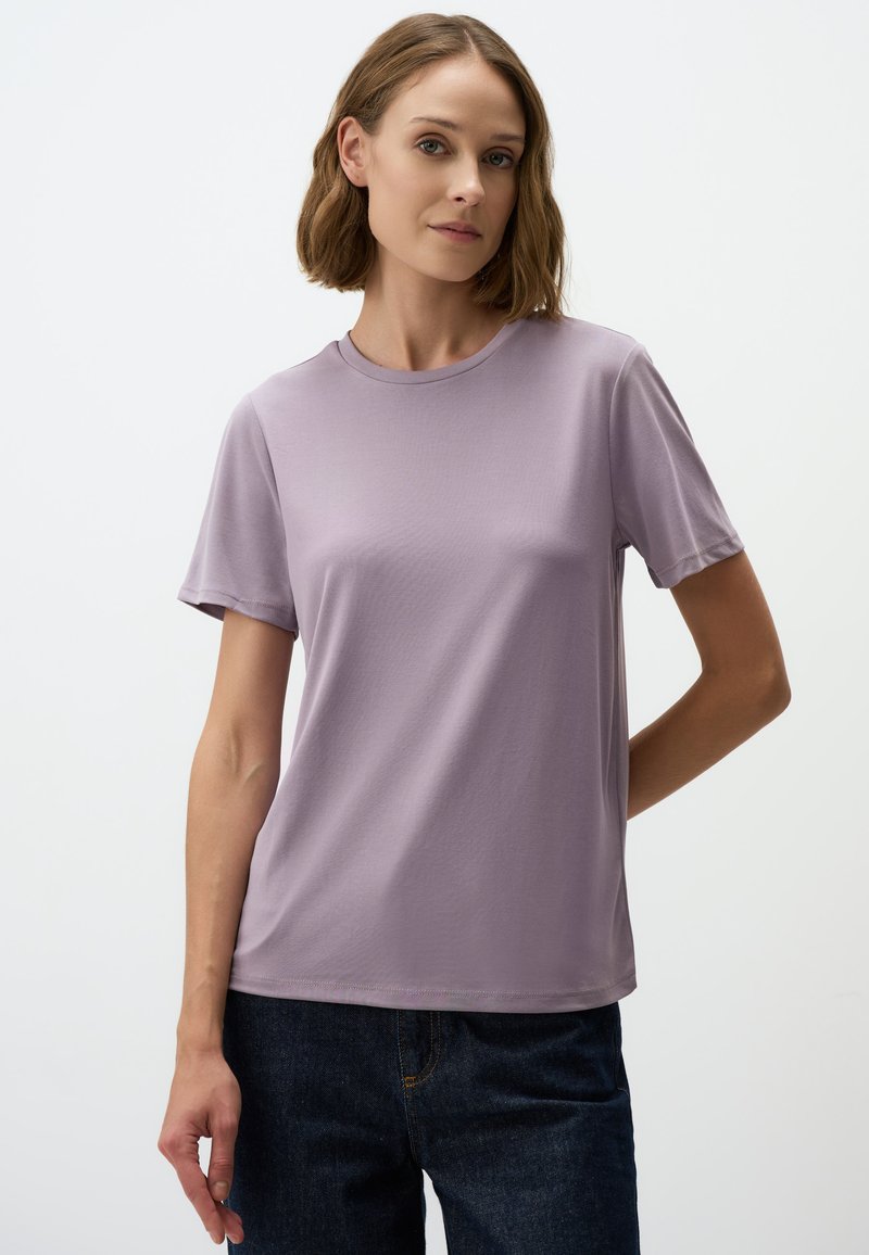 Jasnofioletowa koszulka z krótkim rękawem, okrągłym dekoltem, wykonana z gładkiego materiału. Projekt jest prosty, nie zawiera widocznych wzorów ani akcentów.