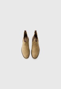 Botas de tobillo de ante marrón claro con paneles laterales elásticos y tiradores, que presentan una textura suave y un diseño de punta redonda.