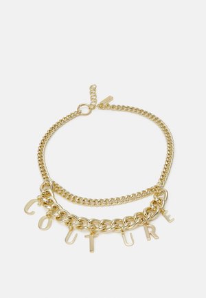 Collier en chaîne dorée avec deux styles de maillons et des pendentifs lettre formant le mot "COUTURE" sur fond blanc.