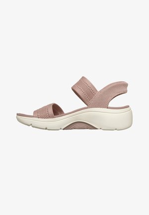 Sandale rose à bout ouvert avec des brides en tissu tricoté et une semelle blanche coussinée conçue pour le confort et le maintien au quotidien.