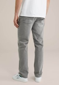Sive jeans hlače s ravnim krojem. Imajo dve zadnji žep in minimalno opremo. Nošene z belimi teniskami.