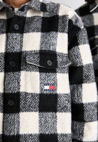 Sort og hvid ternet flannel skjorte med knaplukning foran, brystlomme og Tommy Jeans logo-mærke, der har en blød tekstur og struktureret krave.