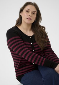 Cardigan rayé noir et bordeaux avec des manches longues, un col rond et une fermeture par boutons. Tissu tricot doux, avec des poignets côtelés.