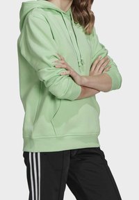 Myntgrön hoodie med en känguruficka och dragsko på huvan. Har ribbade ärmslut och nederkant, tillverkad av mjukt, slätt material.