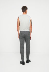 Pantalones a cuadros grises con un corte slim, con un diseño de frente plano y bolsillos traseros, combinados con una blusa sin mangas de color gris claro.