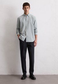 Lichtblauw en wit gestreept overhemd met knopen, gecombineerd met zwarte broek en zwarte schoenen, met een losse fit en lange mouwen.