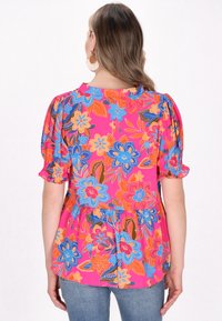 Blomster-pleated top i pink med blå og orange blomster mønstre, puffærmer og en afslappet pasform. Bagview viser den samlet detalje.