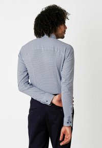 Langarmhemd mit blau-weißen Punktemuster, taillierte Passform, Knopfmanschetten und Rückeneinsatz. Hergestellt aus leichtem Stoff.