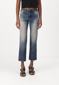 Denimjeans i en medelblå ton med rak benpassform, subtila blekning, femficksdesign och en klassisk knappstängning.