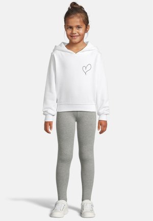 Vit huvtröja med ett hjärtmotiv på bröstet, matchad med grå leggings och vita sneakers, med en avslappnad passform.