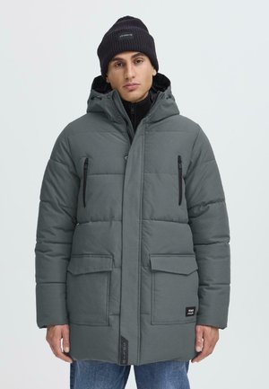 Gray padded coat featuring a zip front, two large front pockets, and a zippered chest pocket. Finished with a black label detail and hood.