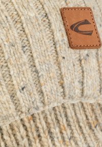 Knit beanie in light beige with flecks of orange and blue. Features a ribbed texture and a brown leather patch with logo detail.