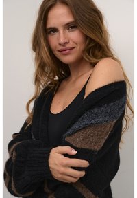 Cardigan nero oversize in tessuto a maglia testurizzata. Presenta righe verticali in grigio e marrone. Maniche con bordi a coste e design aperto davanti.
