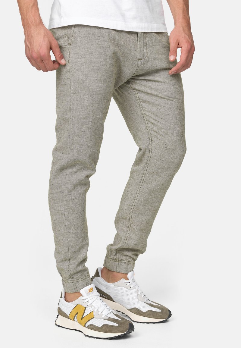 Lichtgrijze jogginbroeken met een gestructureerde afwerking, met taps toelopende pijpen en elastische boorden. Gepaard met witgrijze sneakers.