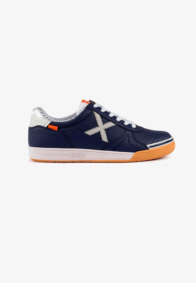 Zapatilla de deporte en color navy con parte superior sintética perforada, acentos grises, cordones blancos, suela de goma y detalle naranja en el talón.
