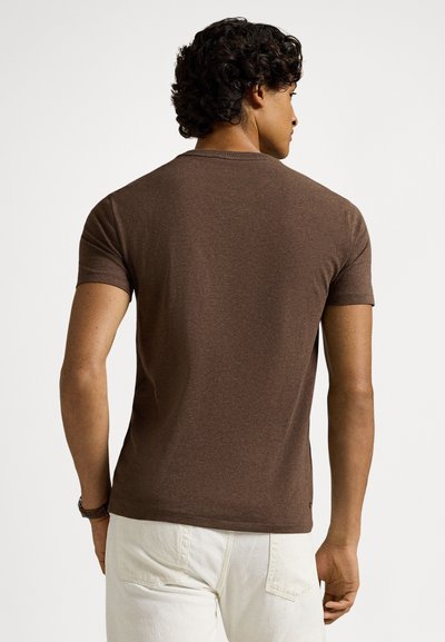 Καφέ κοντομάνικη μπλούζα από απαλό ύφασμα, με κλασικό στρογγυλό λαιμό και εφαρμοστή σχεδίαση, ορατή από πίσω.