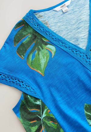 Blå v-ringad topp med en texturerad spetskrage, prydd med livfulla gröna bladtryck och orange detaljer. Lättviktsmaterial, avslappnad design.