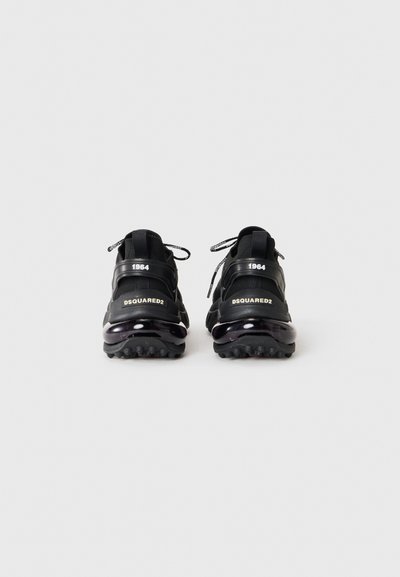 Black athletic shoes featuring a sleek design, textured rubber sole, and prominent branding. Reinforced heel and laces for secure fit.