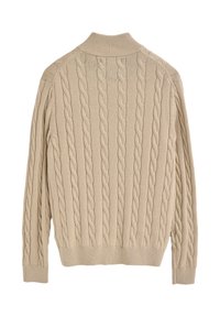 Beige kabelstickad tröja med ribbad krage och mudd, med upphöjda, snurrade mönster över ryggen, tillverkad av mjukt textilmaterial.