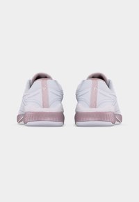 Ζευγάρι αθλητικών παπουτσιών λευκού και ανοιχτού ροζ χρώματος, εμφανιζόμενα από πίσω, με υφή στη σόλα και λεπτομέρειες από δίχτυ στο πάνω μέρος.